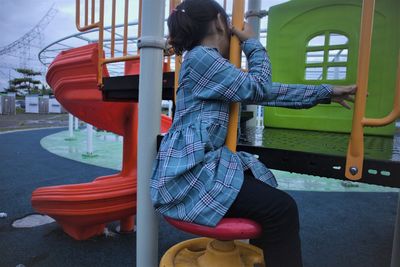 Rear view of woman sitting on seat at playground