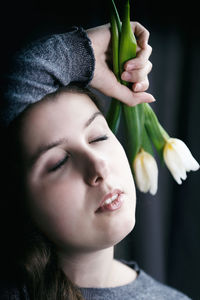 Close-up portrait of a young woman holding flower