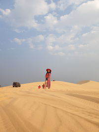 Woman standing at desert against sky