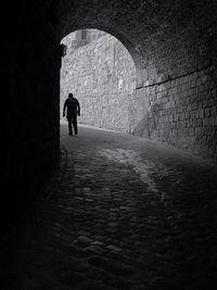Rear view of people walking on footpath in tunnel