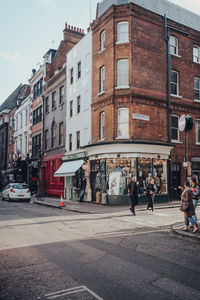 People walking on road by buildings in city