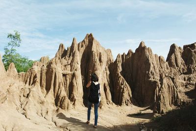 Rear view of man standing on rock against sky