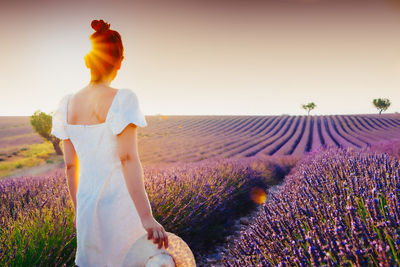 Rear view of woman standing on field against sky