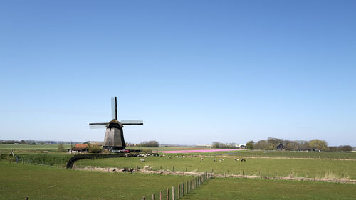 Windmill on field against clear sky