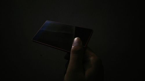 Hand holding mobile phone against black background