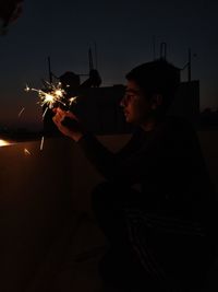 Young man with arms outstretched at night