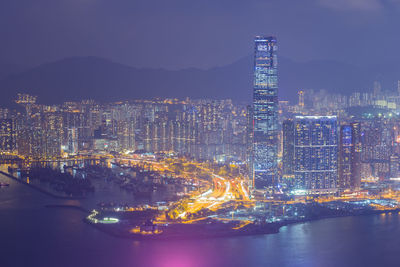 Illuminated city by sea against sky at night