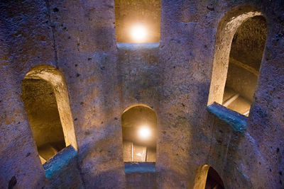 Low angle view of illuminated lighting equipment in building