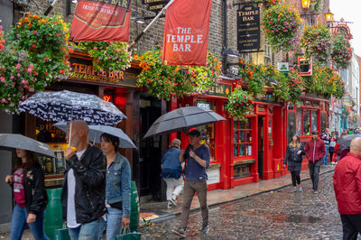 People on wet street in city during rainy season