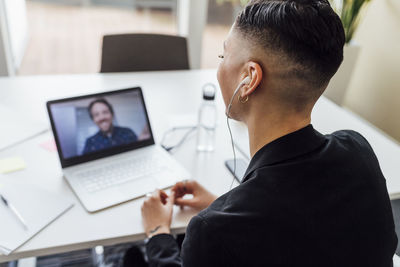 Businesswoman attending meeting through video call on laptop at office