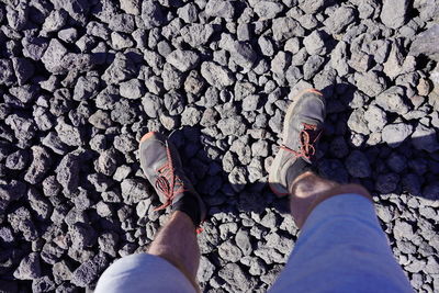 Low section of man standing on pebbles