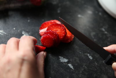 Cropped hand cutting strawberry