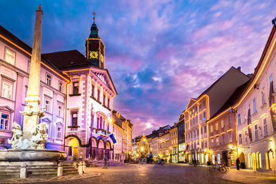 Street amidst buildings against sky at dusk