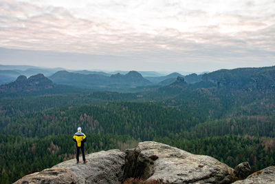 Silhouette of photographer standing on the rocky mountain in rays of sunrise. sudetes