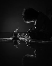 Side view of boy with coffee sitting on floor at home