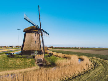 Traditional windmill on field against clear sky