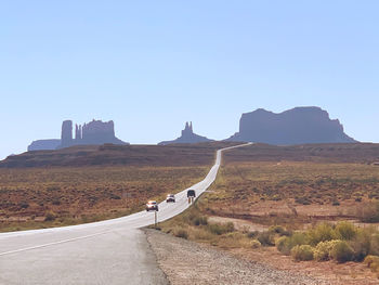 Road leading towards mountain against clear blue sky