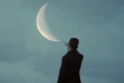 Rear view of silhouette man against moon in sky
