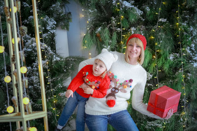 Portrait of smiling young woman standing against trees