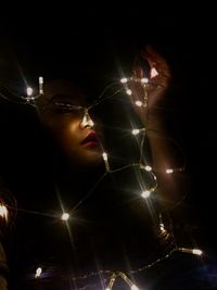 Close-up of woman looking at illuminated lights at night