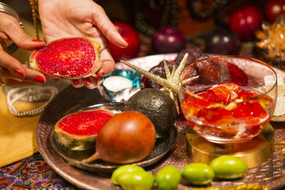 Close-up of hand holding fruits on table