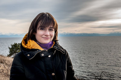Portrait of smiling woman against great lake against sky