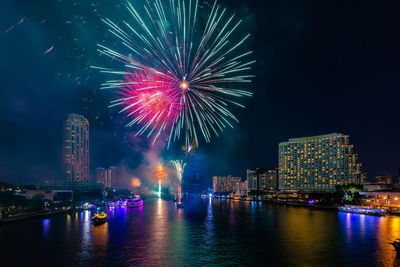 Firework display over illuminated buildings in city at night