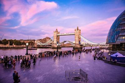 Group of people at bridge in city against cloudy sky