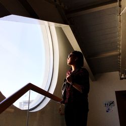 Low angle view of woman standing by window