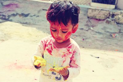 High angle view of baby boy with powder paint while standing outdoors