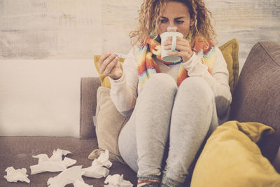 Midsection of woman sitting on sofa at home