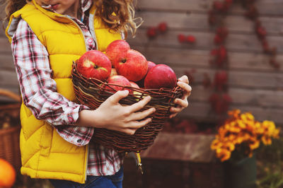 Midsection of woman holding strawberries in basket