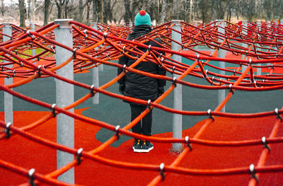 Rear view of person tangled in red rope net in the park