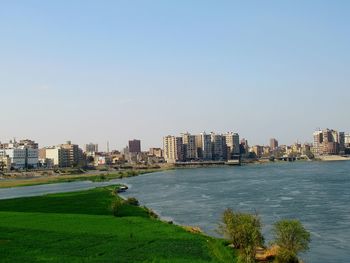 Scenic view of sea by buildings against clear sky