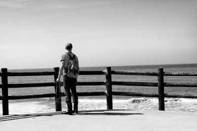 Rear view of man walking on beach against sky