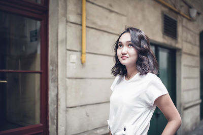 Optimistic asian female student in a white t-shirt, looking up. summer lifestyle portrait