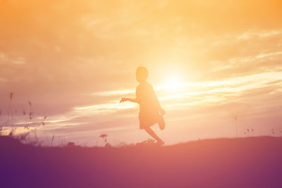 Silhouette woman on field against sky during sunset