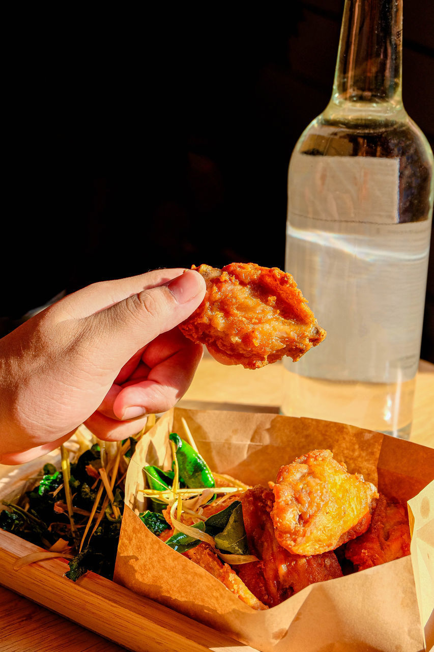 CLOSE-UP OF PERSON HOLDING FOOD ON TABLE