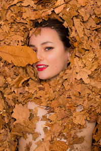 Portrait of a woman covered in autumn leaves