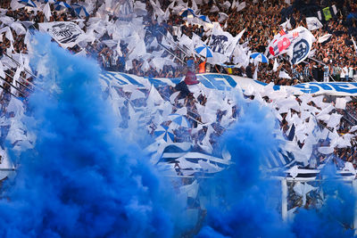 Argentine soccer fans welcome their team with flags, confetti and blue smoke inside a stadium 