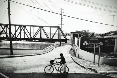 Man riding bicycle on bridge in city