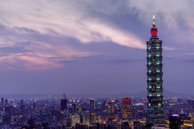 Illuminated taipei 101 in city against cloudy sky