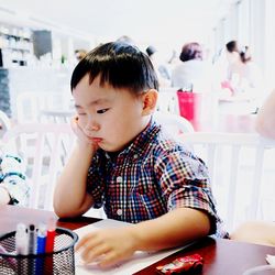 Sad boy sitting on chair at restaurant