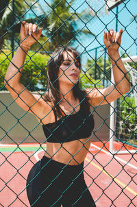 Young woman seen through chainlink fence