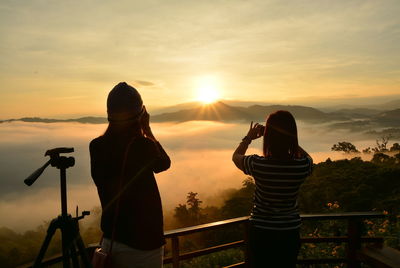 Rear view of people photographing sunset