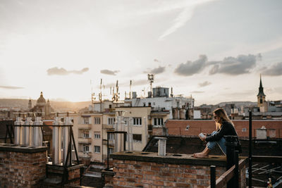 Side view of man looking at city against sky