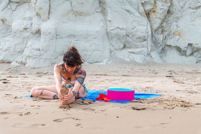 Rear view of girl sitting on sand at beach