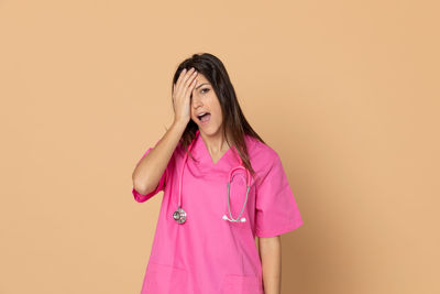 Portrait of woman standing against pink background