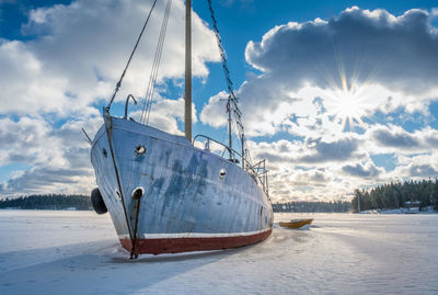 Sailboat on snow covered shore against sky