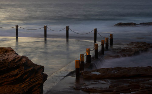 Wooden posts in sea against sky